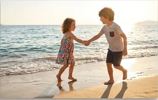 Kinder tanzen am Strand bei Sonnenuntergang